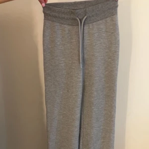 Grå mjukisbyxor med snörning - Säljer ett par bekväma grå mjukisbyxor med snörning i midjan. Byxorna har en loose passform och är perfekta för en avslappnad stil. Tillverkade i mjukt material för extra komfort.