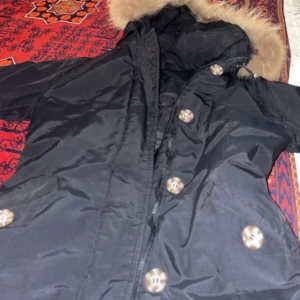 Svart jacka med pälsdetalj - Snygg svart jacka med pälsdetalj på huvan. I bra skick använd 1 vinter 