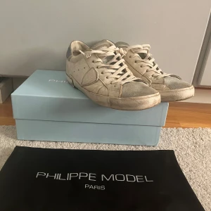  Philippe Model skor - Säljer ett par Philippe Model sneakers i vitt med gröna detaljer och rund tå. Modellen är smutsig i original form men dom skulle behöva en tvätt.  Levereras med originalkartong och dustbag. Äkta köptes för 3500kr