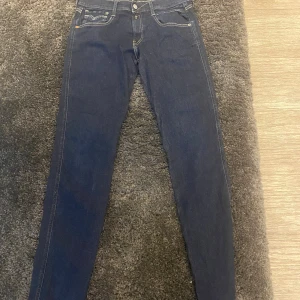 Mörkblå Replay jeansbyxor  - Säljer ett par mörkblå jeans från Replay med skinny fit. Klassisk femficksmodell med gul kontrastsöm och knappgylf. Perfekta för dig som gillar en tajt passform och stilren look.