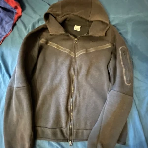 Svart Nike tech fleece hoodie - Svart Nike tech hoodie. Perfekt för kyliga dagar och enkel att matcha med olika outfits. Mjuk och bekväm känsla.