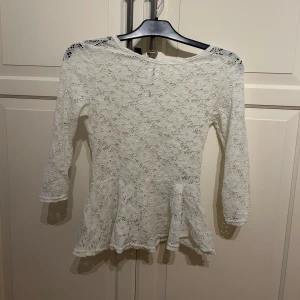 Vit spetstopp från Amisu - Säljer en söt vit spetstopp från Amisu i storlek XS. Toppen är av spets med en lätt utsvängd nederdel. 