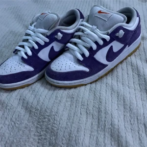 Nike SB Dunk purple court  - Säljer ett par Nike SB Dunk sneakers i lila och vitt eftersom de blivit för små. De är i bra utmärkt skick ock knappt använda. Man får den originella lådan. Skriv om ni har någon fråga.