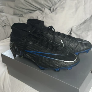 Nike Mercurial elite fotbollsskor i svart och blå - Säljer ett par Nike Mercurial fotbollsskor i svart med blå och silverdetaljer. Nypris 3000. Används ett par gånger men är i väldigt bra skick. 