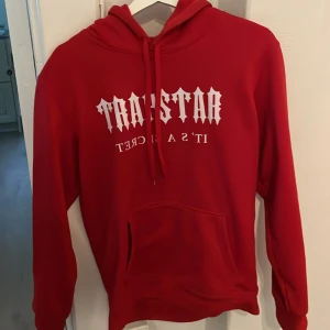 Röd hoodie från Trapstar - Röd hoodie från Trapstar med vit text på bröstet och klassisk huva med dragsko. Stor magficka framtill och mjukt material som passar perfekt till vardags. Snygg streetstil med avslappnad passform. Pris kan diskuteras 