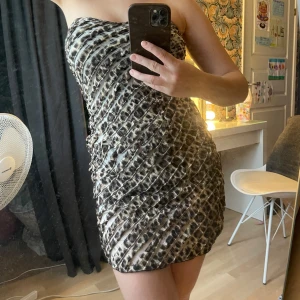 Leopard miniklänning bandeau  - Kort beandeuklänning i leopardmönster. Snygga volangdetaljer över hela klänningen. Passar Xs/S. 