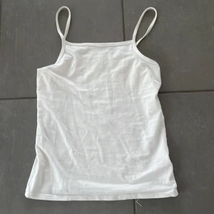 Vit linnetopp från H&M - Säljer en enkel och stilren vit linnetopp från H&M med smala axelband. Perfekt att bära under varma dagar eller som lager under andra plagg. Tunn och mjuk bomullskvalitet.