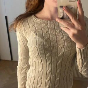 Beige kabelstickad Ralph lauren tröja - Säljer en beige kabelstickad tröja med rund halsringning från Ralph Lauren. Perfekt till sommar kvällar. Den är för liten för mig så därför ser den lite uttöjd ut.