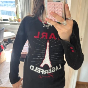skitsnygg tröja från karl lagerfeld  - Säljer en svart långärmad tröja från Karl Lagerfeld med Eiffeltornet och strasstenar framtill. Röda detaljer vid halsringning och knappar på ärmen. Köpt i usa för ca 700kr!! Skitsnygg med röda knappar vid handen!! kp för frågor❤️