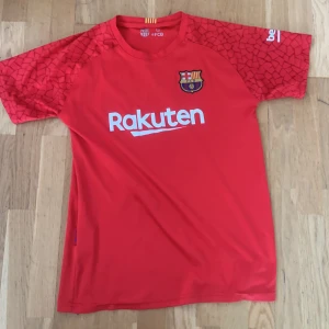 FC Barcelona målvaktströja Ter Stegen - Röd FC Barcelona målvaktströja med Ter Stegen och nummer 1 på ryggen. Tröjan har korta ärmar med mönstrade detaljer och klubbmärke på bröstet. Rakuten och Unicef-loggor tryckta på framsidan och baksidan.