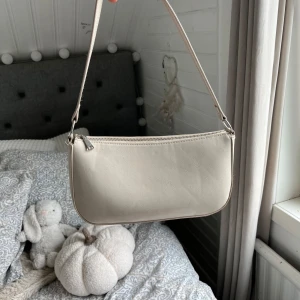 Beige axelväska  - Beige axelremsväska från hm. Väl använd därav ser botten i väskan ut så men annars är den fin utvändigt 