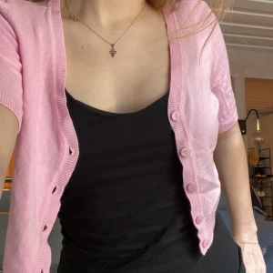 Ljusrosa croppad kofta från Stockh lm - Säljer en söt ljusrosa croppad kofta från Stockh lm. Koftan har korta ärmar, v-ringning och knäppning framtill. Perfekt att styla över ett linne eller klänning för en fräsch look.