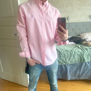 Rosa rutig skjorta från Polo Ralph Lauren - Säljer en rosa och vit rutig skjorta från Polo Ralph Lauren i slim fit-modell. Skjortan har långa ärmar, klassisk krage, knappar framtill och den ikoniska broderade loggan på bröstet. Perfekt för dig som gillar stilrena och klassiska plagg samt sjukt fräsch till sommaren! 