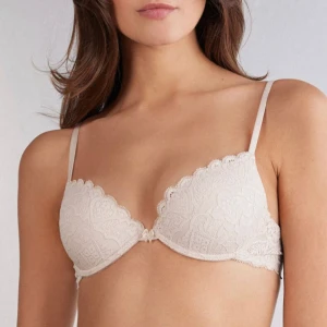 Intimissimi bh - Säljer en Intimissimi bh med spetsdetaljer i färgen ”Avorio Crema”. Bh:n har tunna axelband och en liten rosett framtill. Perfekt för dig som gillar en feminin och stilren look. Använd max en gång om äns det!💓 Den är lite insydd så den är lite lite tajtare runt om