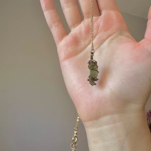 Moldavit halsband  - Äkta moldavit, gjord till ett halsband. Metalltråden har rostad där stenen ligger. 0.7x2cm. Kedja 46cm går att justera. 