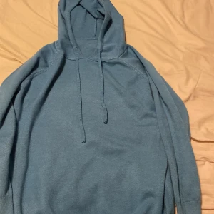Merinoull hoodie - Säljer en stilren blå hoodie med långa ärmar och justerbar huva. Perfekt för en avslappnad look. Passar bra till jeans eller träningsbyxor. Passar mig men börjar bli för liten är 173 typ