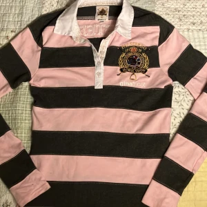 Randig pikétröja från Gina Tricot x Falsterbo Horse Show 1920 - Säljer en rosa och mörkgrå randig pikétröja från Gina Tricot x Falsterbo Horse Show. Å brodyr på bröstet och stor text på ryggen. Klassisk vit krage och knäppning framtill. Perfekt för dig som gillar hästtema och sportig stil. HELT OANDVÄND. Original pris 499kr.