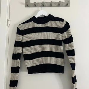 Svart och beige randig stickad tröja - Stickad randig tröja i storlek S, väldigt liten i storlek och kort i längden. 