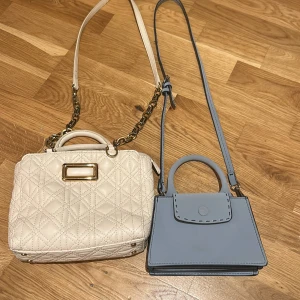 Ljusblå mini axelväska med handtag - Supersöt ljusblå mini axelväska med både handtag och lång axelrem. Väskan har en stilren design med dekorativa sömmar och stängs med lock. Perfekt för dig som vill ha en liten och trendig accessoar till din outfit.