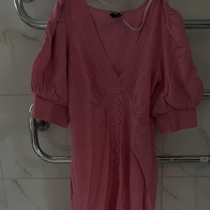 Rosa klänning med slits  - Jättefin rosa sommarklänning från VeroModa (adoore liknande) i storlek XS. Fluffig vid armen, knappar längs klänningen och slits framtill. Använd en gång i somras— så i bra skick utan några defekter!! Jättefin nu inför sommaren, midsommar eller andra tillfällen☀️😊. Är 165cm lång. Osäker om jag vill sälja den så börjar med 400kr, pris går att diskutera. Minns ej hur mycket jag köpte den för men kan gissa på 499-599 🤷🏽‍♀️ för fler bilder & info kom pm💗