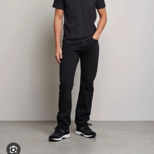 Svarta straight jeansbyxor Levis 501 - Snygga svarta jeansbyxor med rak passform. Klassisk design utan synliga detaljer, perfekt för en stilren look. Passar till det mesta och är lätta att matcha med olika skor och tröjor.