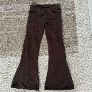 Bruna manchesterbyxor  - Säljer ett par bruna manchesterbyxor från Run & Fly med utsvängda ben och snygga kontrastsömmar på bakfickorna. Perfekta för dig som gillar retrostil! Finns ingen storlek på dem (i byxan står size 30s men osäker vad det innebär) men de skulle passa någon i 34 eller 32. 