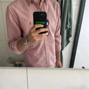 Rosa skjorta från Ralph Lauren - Riktigt snygg rosa skjorta och perfekt till sommaren! Nypris 1995 kr.                                                Axelbredd - 40 cm           Längd - 63 cm                 Smal passform och passar Small/Medium