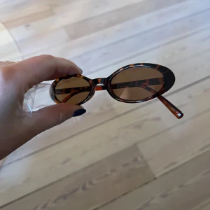 Ovala solglasögon med leopardmönster - Snygga ovala solglasögon med brunt leopardmönstrat båge och bruna glas. Perfekt accessoar för att lyfta din stil med en retrovibe. Lätta och bekväma att bära.