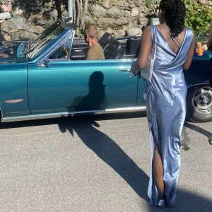 Ljusblå långklänning med draperad axel - Pris! Kan alltid diskuteras. Elegant ljusblå långklänning med draperad axel och vacker omlott-detalj i ryggen. Klänningen har en slits på sidan och är tillverkad i ett glansigt material som ger en lyxig känsla. Perfekt för speciella och balen. Satin 