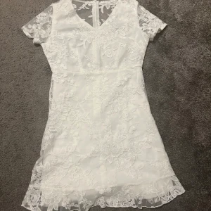 Vit klänning med blommigt mönster - Säljer en superfin vit kortklänning med blommig spets och v-ringning. Klänningen har jättefina detaljer och är perfekt till student eller skolavslutning! skriv för mer bilder! Pris går att diskuteras!