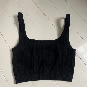Svart ribbad linnetopp från Zara - Säljer en svart ribbad linnetopp från Zara. Toppen har breda axelband och är croppad i modellen, perfekt att matcha med höga jeans eller kjol. Enkel och stilren design som passar till många olika looks. Skriv för fler bilder💞