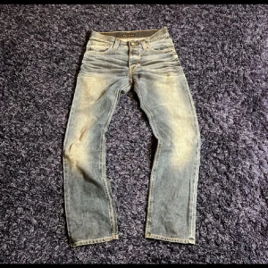  Nudie Jeans average Joe - Säljer ett par klassiska blå jeans från Nudie Jeans med raka ben och normal passform som heter average joe. Jeansen har fem fickor, ljusa slitningar och en läderpatch bak i midjan. Perfekta för en avslappnad stil. Storlek 30/32 skulle dock säga att midjan är lite mindre än vanligt. Pris kan diskuteras