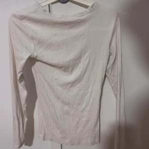Vit långärmad topp  - En enkel och stilren vit långärmad topp från H&M. Modellen är tight och har rund halsringning. Perfekt att matcha med jeans eller kjol för en clean look.
