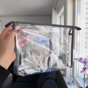 Transparent necessär med grå dragkedja - Säljer en genomskinlig necessär med grå kant och dragkedja. Perfekt för att hålla koll på småsaker eller smink. Enkel och stilren design som gör det lätt att se innehållet. Önskar du veta exakta mått? Tveka inte att höra av dig 🤍