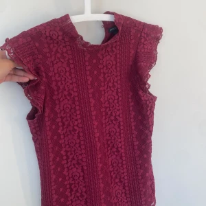 Vinröd spetsblus från Stockh LM - Säljer en vinröd blus från Stockh LM i vacker spets med mönster. Blusen har korta volangärmar och rund halsringning. 🍒🌺