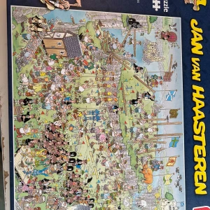 Jan van Haasteren pussel - Rolig och detaljrik pussel från Jan van Haasteren med ett medeltida tema. Kartongen visar en färgglad och humoristisk illustration med många figurer, byggnader och flaggor. Perfekt för dig som gillar utmanande pussel och skojiga motiv. Började pussla det men avslutade aldrig så knappt använt