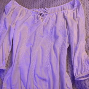 Vit offshoulder blus med knyt från L.O.G.G. H&M - Säljer en vit offshoulder blus från L.O.G.G. H&M i bomull med broderade detaljer. Blusen har trekvartsärm, knytning fram och smock vid ärmslut. Perfekt för vår och sommar! En sminkfläck fram som syns men om någon är intresserad kan jag fixa bort den🥰