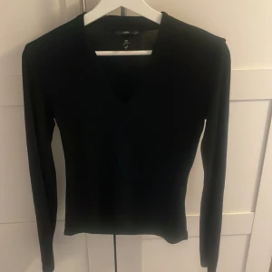 urringad långärmad topp - Säljer en svart långärmad topp från H&M med v-ringning. Modellen är tight och passar perfekt till många olika outfits. Enkel och stilren design som är lätt att matcha.