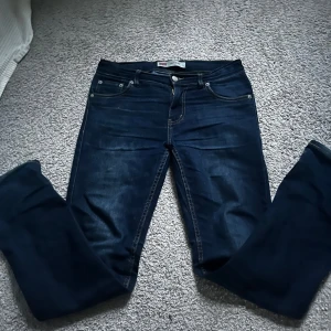 Levi's 511 Slim jeans i mörkblå denim - Säljer ett par klassiska Levi's 511 Slim jeans i mörkblå tvätt. Jeansen har fem fickor, dragkedja och knapp framtill samt snygga kontrastsömmar. Perfekta för dig som gillar en smalare passform och tidlös stil.