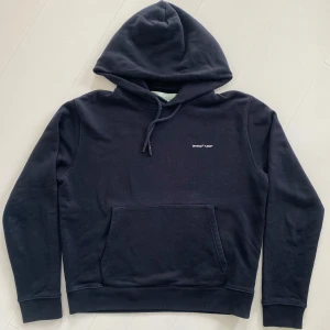 Svart hoodie från Off-White - Säljer en svart hoodie från Off-White med liten vit logga på bröstet. Tröjan har huva med dragsko och en stor magficka framtill. Perfekt för en avslappnad och stilren look. Boxyfit. Nypris 6000kr, köpt på Natalie Schultherman
