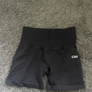 Svarta träningstights shorts från ICANIWILL - Svarta shorts från ICANIWILL. Tillverkade i stretchigt syntetmaterial, perfekta för träning. Liten diskret ficka i linningen. Snygg och enkel design med logga framtill.