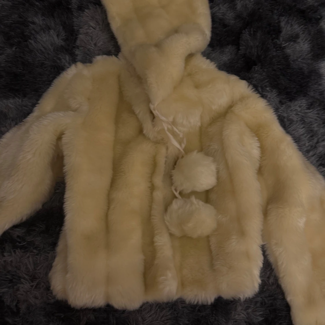 Beige pälsjacka med luva och tofsar