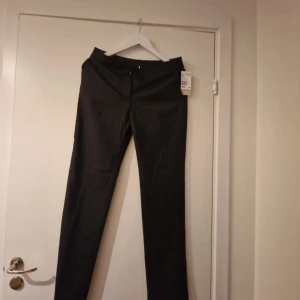 Svarta kostymbyxor från H&M - Snygga svarta kostymbyxor från H&M med klassisk passform och raka ben. Perfekta för en stilren look. Byxorna har diskret knapp och dragkedja framtill.