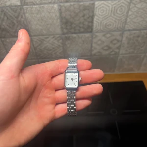 Silver klocka  - Helt oanvänd klocka med justerbart armband och nytt batteri. Den är gjort av 100% rostfrittstål. Armbandet justera du lätt hemma med hjälp av en nål. 