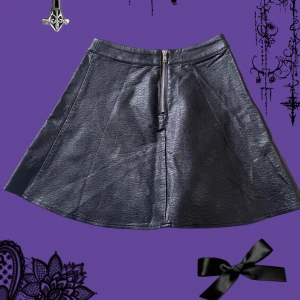 Svart skinnkjol med dragkedja - Säljer en svart läderkjol med  dragkedja fram. Kjolen har en lätt utställd form och midjehög passning, fantastisk skick andvänd ungefär tre gånger! 