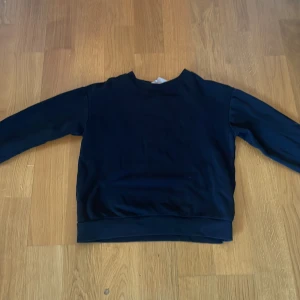 Svart sweatshirt från H&M - En enkel svart sweatshirt från H&M med rund halsringning och långa ärmar. Perfekt för en avslappnad stil och lätt att matcha med andra plagg. Klassisk modell utan tryck eller detaljer.