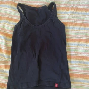 Svart linnetopp från edc by Esprit - Svart enkel linnetopp från edc by Esprit. Klassisk modell med rund halsringning och breda axelband. Perfekt att matcha med jeans eller kjol. Mjukt bomullsmaterial för skön känsla.