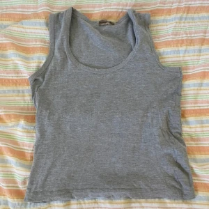 Grå linnetopp från Dressed Up - En enkel och stilren grå linnetopp från Dressed Up. Toppen har rund halsringning och är ärmlös, perfekt för varma dagar eller som lager under andra plagg.
