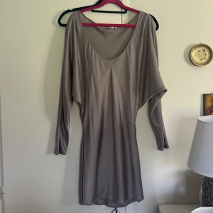 Grå långärmad satinklänning - Säljer en grå långärmad satinklänning med lös passform och djup rundringning. Passar till alla årstider🥰 så fin till exempelvis nyår! säljer billigt då jag tänker skänka bort kommande veckan om det inte blir sålt! Köp!🥰🥰