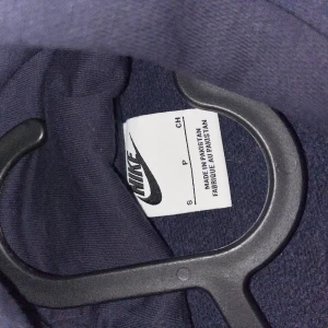 Mörkblå hoodie från Nike med Tottenham Hotspur-logga - Säljer en mörkblå hoodie från Nike med Tottenham Hotspur-logga på bröstet. Tröjan har huva, magficka och är tillverkad i mjukt material. Perfekt för dig som gillar fotboll och vill ha en stilren och sportig look.